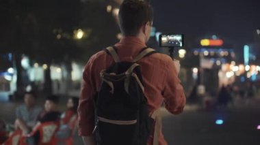 Adam gece kentinde yürüyüş videosu çekiyor.
