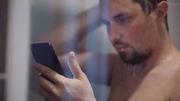 Man met nomofobie gebruikt smartphone onder de douche — Stockvideo