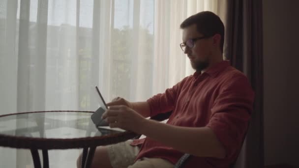 Чоловік працює з планшетом у вітальні — стокове відео