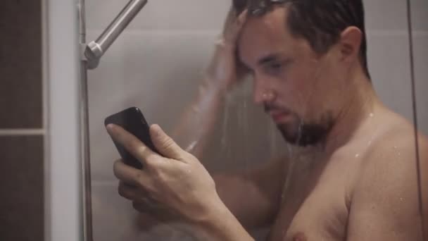 Humano con teléfono celular en la ducha, cabeza de lavado — Vídeos de Stock