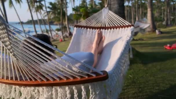 Расслабляющий мужчина лежит в гамаке у побережья океана — стоковое видео