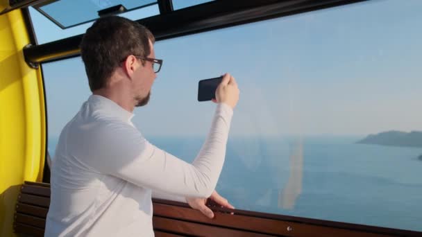 Turista está fotografiando vista al mar desde teleférico — Vídeos de Stock