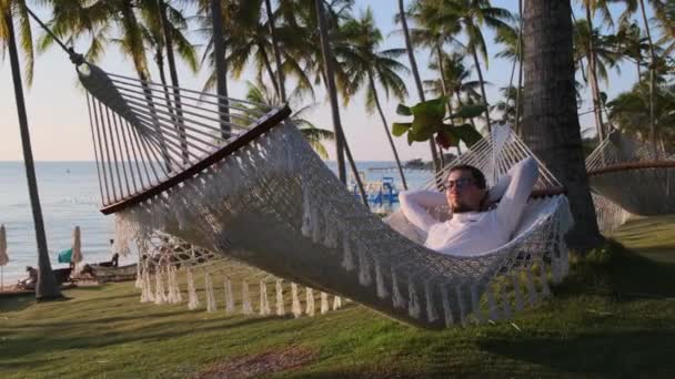 Nothing is bothering him now. Relaxing in swinging hammock on the beach — Stock Video