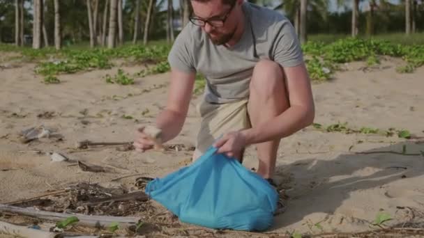 Man die zwerfvuil oppikt op het strand — Stockvideo