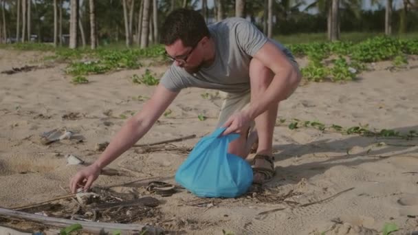 Human is collecting non-degradable waste on seashore — Stock Video