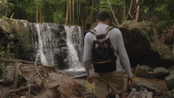 Turista homem está andando na floresta na Ásia, vendo cachoeiras — Vídeo de Stock