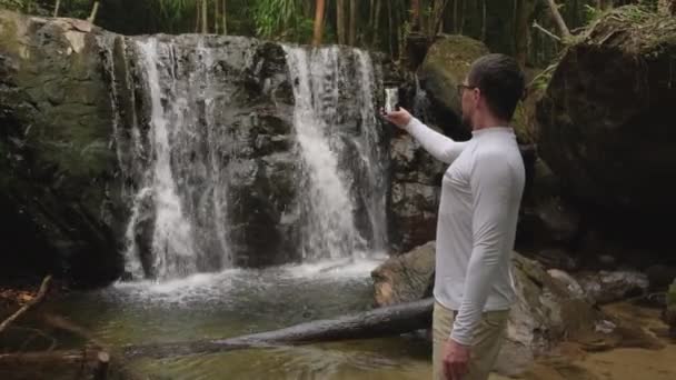 Hombre está filmando cascadas en el bosque por teléfono celular — Vídeo de stock