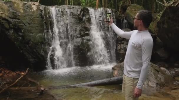 Wandelaar neemt video van waterval in het bos — Stockvideo