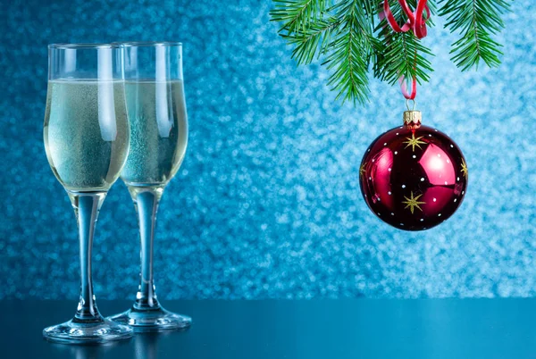 Masanın üzerinde iki kadeh şampanya ve yeni yıl oyuncakları var.