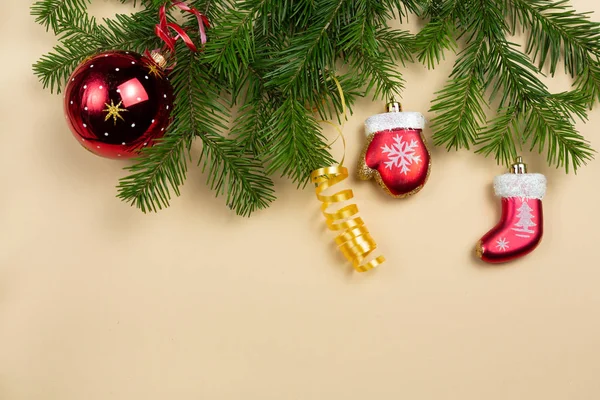 Üniformalı bir arka planda ladin dalları ve yeni yıl oyuncakları uzanıyor.