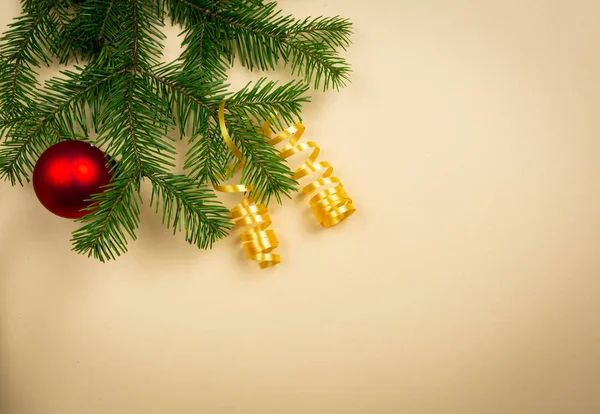 Üniformalı bir arka planda ladin dalları ve yeni yıl oyuncakları uzanıyor.