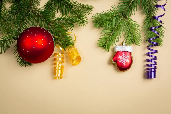 Üniformalı bir arka planda ladin dalları ve yeni yıl oyuncakları uzanıyor.