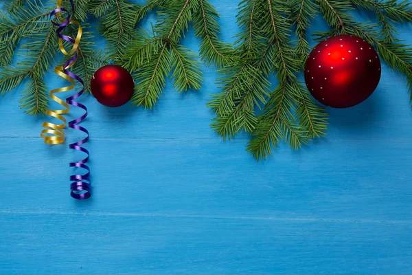 Üniformalı bir arka planda ladin dalları ve yeni yıl oyuncakları uzanıyor.