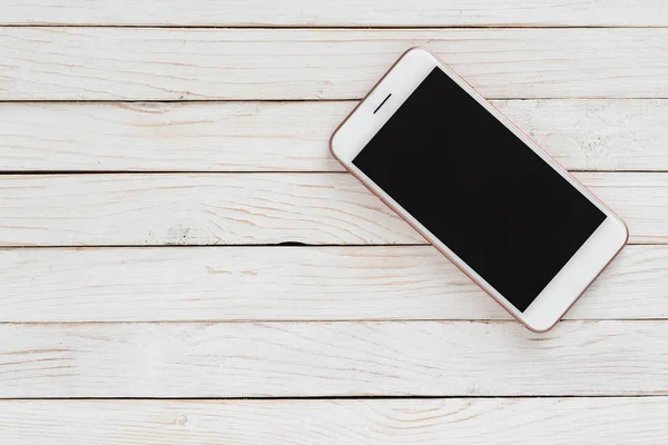 Beyaz ahşap arkaplanda siyah ekranlı akıllı telefon iPhone