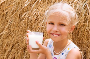 Fon karşı cam bir Haystack bir çiftlikte inek sütü kız içecekler.