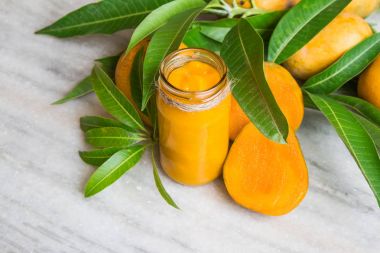 Mango ev yapımı reçel taze meyveleri ve mango yaprakların üzerinde beyaz mermer.