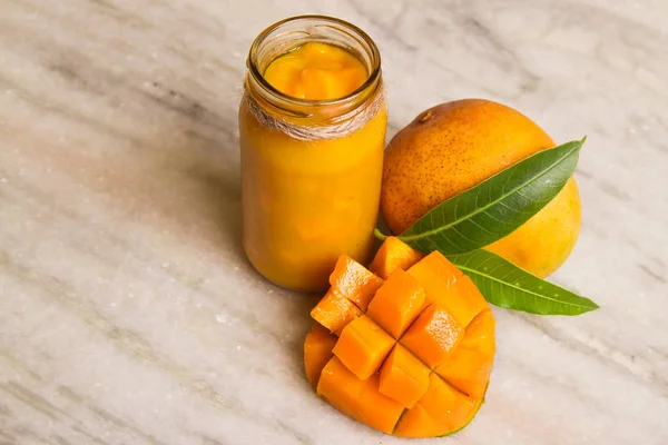 Zelfgemaakte Jam Mango met vers fruit en bladeren van mango op een wit marmer. — Stockfoto