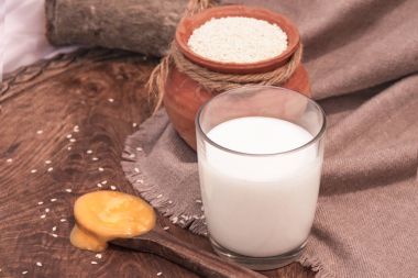 Bir tablo üzerinde toprak kap içinde cam ve susam tohumu sütte susam.