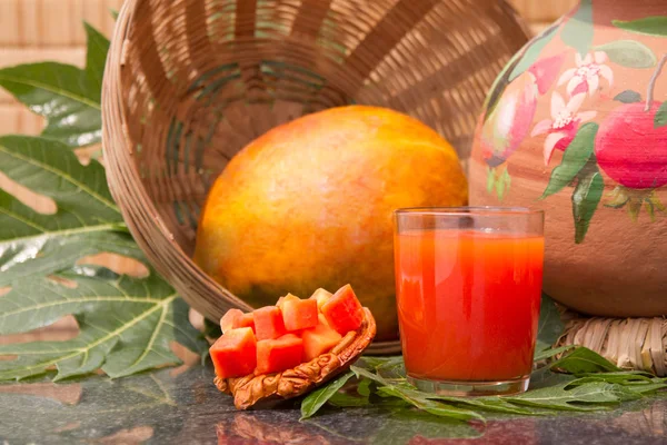 Sumo de mamão fresco no copo com frutas de mamão, folhas e fatias — Fotografia de Stock