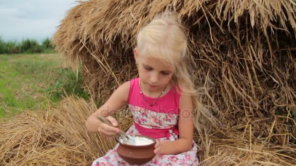 Όμορφο κορίτσι τρώει γιαούρτι γλυκό από ένα πήλινο καπάκι. — Αρχείο Βίντεο
