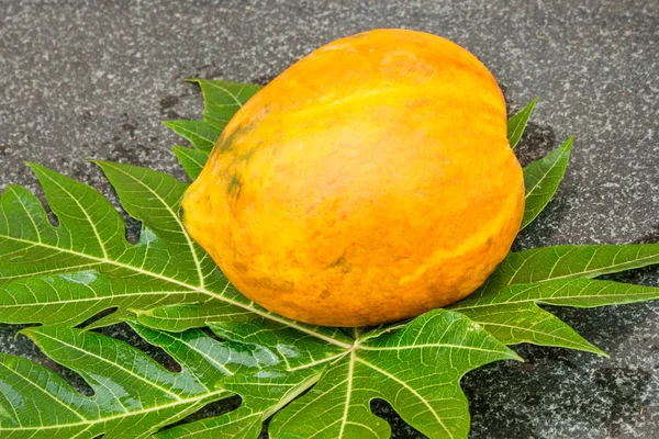 Fresh sweet papaya fruit and papaya leaf on a granite table. — Stockfoto