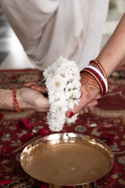 Matrimonio tradizionale indiano. autentico rituale di matrimonio vedico chiamato vivaha Yajna. Red Sari, mani di donne con mehendi primo piano. ghirlande di fiori. Rituale del fuoco sacro. coppia multinazionale . — Foto Stock