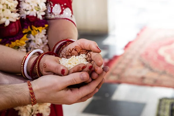 Matrimonio tradizionale indiano. autentico rituale di matrimonio vedico chiamato vivaha Yajna. Red Sari, mani di donne con mehendi primo piano. ghirlande di fiori. Rituale del fuoco sacro. coppia multinazionale . — Foto Stock