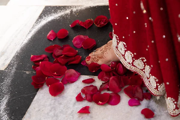 Indian traditional wedding. authentic Vedic wedding ritual called vivaha Yajna. Red Sari, women foot with mehendi close-up on red rose petals. Sacred fire ritual. multinational couple. — Stock Photo, Image