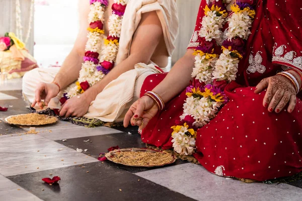 Matrimonio tradizionale indiano. autentico rituale di matrimonio vedico chiamato vivaha Yajna. Red Sari, mani di donne con mehendi primo piano. ghirlande di fiori. Rituale del fuoco sacro. coppia multinazionale . — Foto Stock