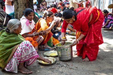 Shantipur, Batı Bengal, Hindistan - 7 Mart 2020. Kırmızı Sari 'li Hintli kadın Santipur Festivali sırasında geleneksel Hint yemeği khichdi prasadam dağıtıyor. Hindistan 'da bedava yiyecek dağıtımı