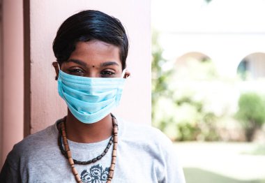 Koronavirüs. Koruyucu tıbbi maske takan koyu tenli güzel bir genç kızın portresi. Corona virüsü karantinası, Covid-19. Afrikalı yetişkin kız hastalıklarının önlenmesi. Askerler!
