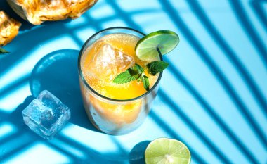 Bel meyvesinden egzotik meyve suyu ya da Bel Ka Sharbat adında ahşap elma suyu. Buzlu soğuk meyve suyu ve mavi arka planda güneş ışığıyla ışıldayan Bel meyve dilimleri. Palmiye yapraklarının gölgesi. en üstteki görünüm