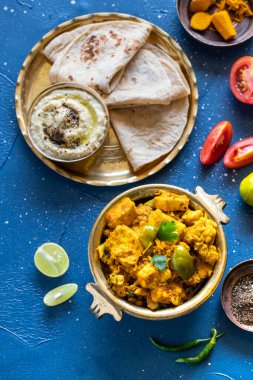 Doğu yemekleri - Hint paneer sabji chapati ve soslu. Hint mutfağı. Bakır pirinçten Hint körisi, mavi arka plandaki malzemelerle yakın plan, Hint yemeği seti.