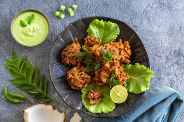 Hint mutfağı. Pakora geleneksel Hint kızartılmış atıştırmalığı. Hindistan cevizi soslu siyah tabakta pakoralar. Ulusal aperatif otantik vejetaryen yemekleri. Asya seyahati yemeği. Üst Manzara. Boşluğu kopyala