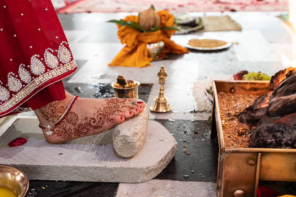 bride in a red Sari. Beautiful traditional Indian wedding ceremony. bride's foot is decorated with mehendi. Hindu wedding. indian engagement. Hindu the Vedic Yagya ceremony. vivah Yajna