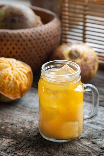 exotic fruit juice from Bel fruit or wooden Apple called in India Bel Ka Sharbat. cold fruit drink with ice and Bel fruit slices on wooden rustic background. natural detox. vitamins for immunity.