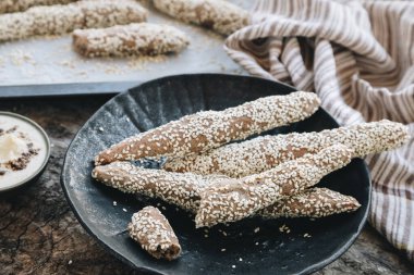 Yeni pişirilmiş ev yapımı ekmek çubukları susam, ev yapımı mayonez, humus ya da ahşap bir masada beyaz sos. Köy yemekleri. Kırsal biçim.