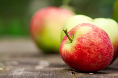 Ev yapımı kırmızı organik elma meyveleri yaz bahçesindeki ahşap masa üzerinde. Organik çiğ vejetaryen sağlıklı gıdaları kapatın. Yaz rengi. Biyolojik gıda..