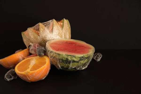 Fruits packed in plastic film on black background — Stock Photo, Image