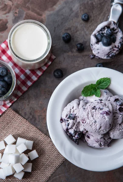 ミントの葉や石のスレートの背景にアイスクリームのスプーンとブルーベリーの自家製アイスクリーム — ストック写真