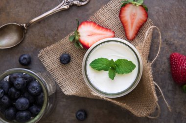 Ev yapımı yoğurt, ekşi krema yaban mersini, çilek ve nane ile taş arduvaz arka plan üzerinde bırakır..