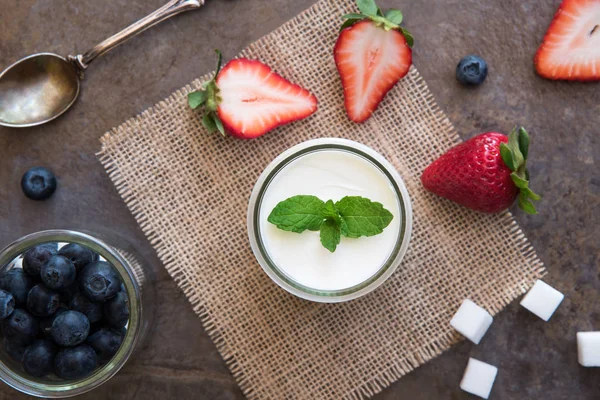 Yogur casero, crema agria con arándanos y fresas, y hojas de menta sobre fondo de pizarra de piedra . —  Fotos de Stock