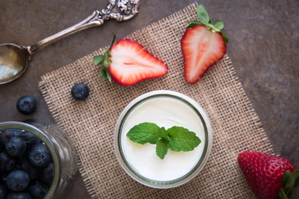 Yogur casero, crema agria con arándanos y fresas, y hojas de menta sobre fondo de pizarra de piedra . —  Fotos de Stock