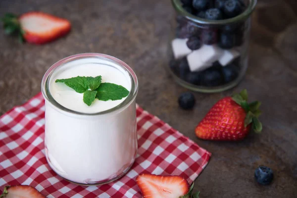 Házi joghurt, tejföl, a fekete áfonya és eper, kő pala háttér. — Stock Fotó
