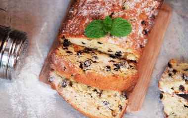 Pudra şekeri ve nane ile serpilir üzümlü geleneksel kek dekore edilmiş bırakır. Mermer gri arka plan