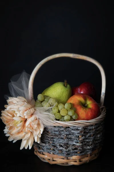 Surtido de frutas frescas crudas en canasta de mimbre sobre fondo negro. Con espacio de copia — Foto de Stock