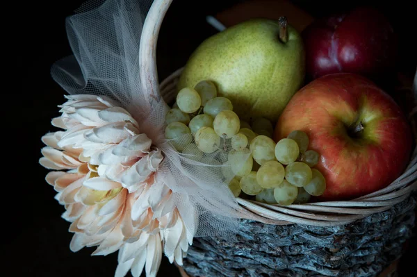 Surtido de frutas frescas crudas en canasta de mimbre sobre fondo negro — Foto de Stock