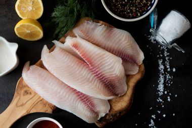 Taze balık fileto pişirme ve baharat doğrama tahtası üzerinde malzemelerle