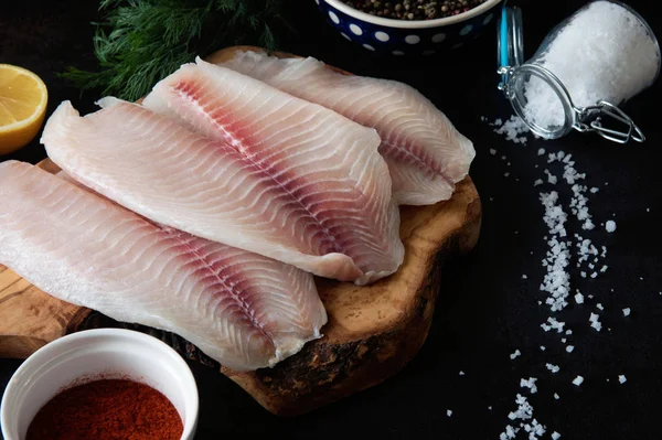 Филе свежей рыбы с ингредиентами для приготовления пищи и приправы на доске — стоковое фото