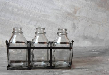 Gri arka planda üç boş cam şişe..